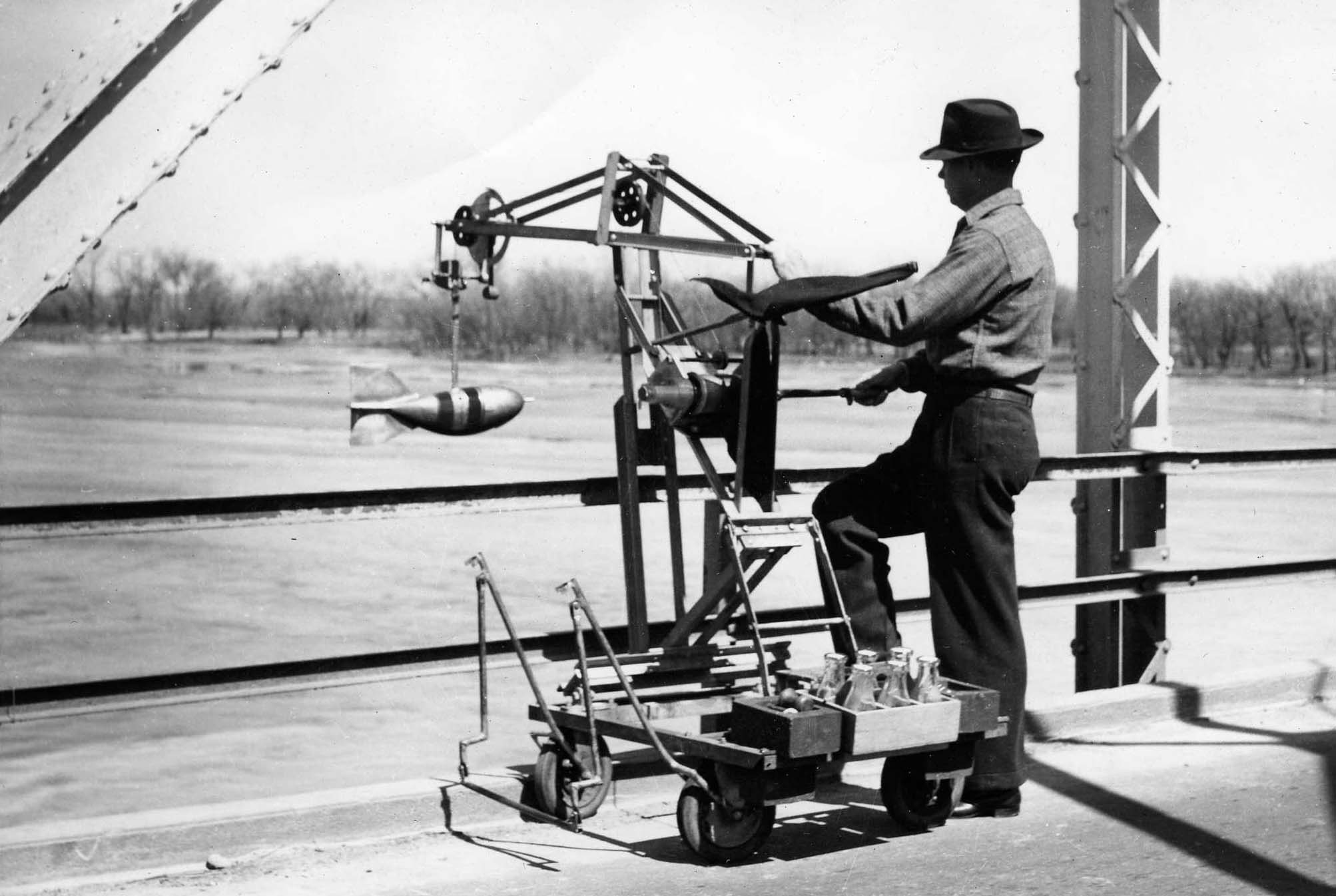 A USGS hydrographer collecting a water quality sample from a bridge over a Nebraska river, April 20, 1947